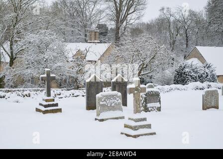 Grabsteine in St. Marys Kirchhof im Schnee. Swinbrook, Cotswolds, Oxfordshire, England Stockfoto