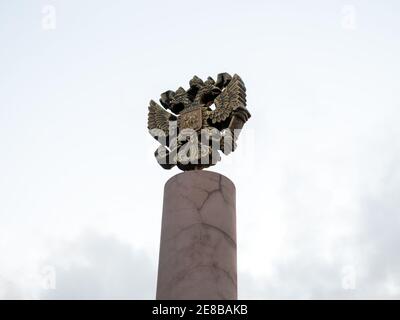 Das Wappen Russlands ist das offizielle Staatssymbol der Russischen Föderation (1993), das auf der Spitze der Säule gegen den Himmel in Bronze gegossen ist. Stockfoto