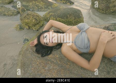 Junge schöne asiatische Frau denken Im liegen und auf den Felsen der öffentliche Strand in Hua Hin Thailand posing Stockfoto