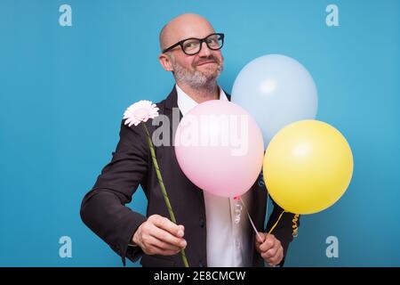 Geburtstagsgrüße. Mann in Anzug halten Luftballons und Blume. Gentleman macht romantische Überraschung für sie. Stockfoto