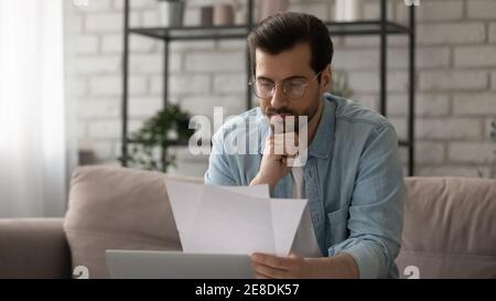 Nahaufnahme ernster Mann trägt eine Brille, liest Brief, prüft Dokumente Stockfoto