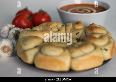 Hausgemachte gesunde Tomatensuppe gepaart mit frisch gebackenem Abendessen Brötchen mit Knoblauchbutter und italienischem Kraut Stockfoto