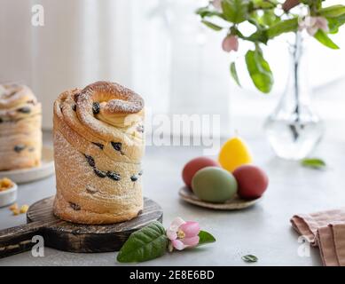 Osterkomposition mit Cruffin Kulich, bemalte Eier, blühender Apfelzweig Stockfoto