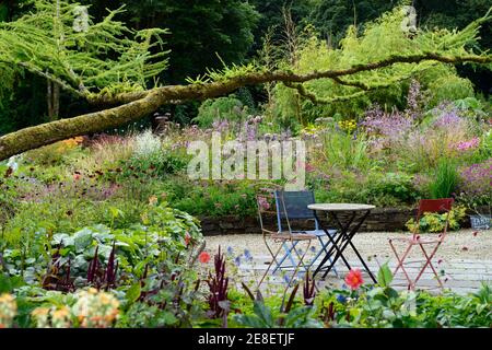 Terrasse Sitzbereich, Sitze, Tisch und Stühle, gemischte mehrjährige Grenze, gemischte mehrjährige Bett, Juni Blake's Garten, Wicklow, Irland, Sommer im Garten, Sitzgelegenheiten Stockfoto