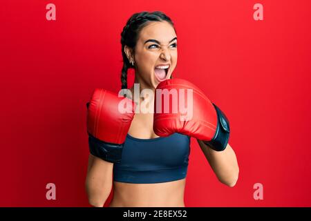 Junge Brünette Mädchen mit Boxhandschuhen wütend und verrückt schreien frustriert und wütend, schreien vor Wut. Wut und aggressive Konzept. Stockfoto