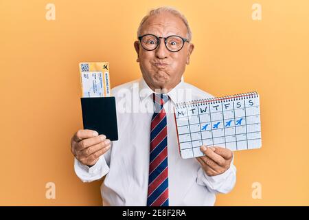 Senior kaukasischen Mann geht auf Geschäftsreise mit Bordkarte puffing Wangen mit lustigen Gesicht. Mund mit Luft aufgeblasen, Luft fangen. Stockfoto