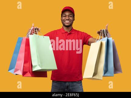 Schwarz Lieferung Kerl hält bunte Taschen im Studio Stockfoto