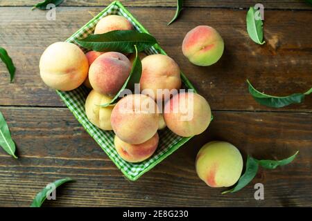 Reife Pfirsiche im Korb auf Holzhintergrund. Hausernte aus dem eigenen Garten. Gesunde Ernährung. Stockfoto
