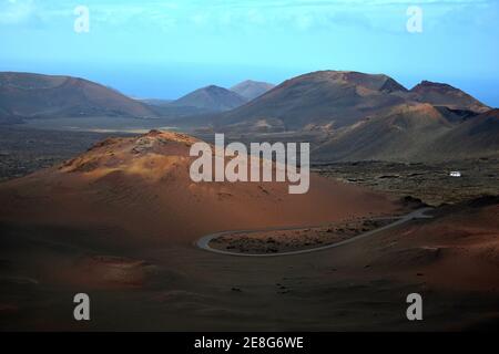 Bunte Vulkanlandschaft im Timanfaya Nationalpark. Lanzarote, Kanarische Inseln, Spanien. Die Straße durch den Nationalpark. Ein weißer Bus auf der r Stockfoto