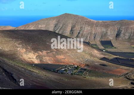 Blick auf ein Tal mit Feldern für die Landwirtschaft. Im Hintergrund die Bergkette Los Ajaches. In Der Nähe Von Femés. Lanzarote, Spanien. Stockfoto