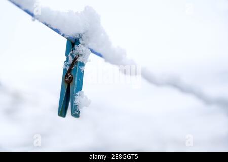 Blaue Kleiderscheren mit Schnee bedeckt hängen auf einer Wäscheleine im Winter, Kopierraum, ausgewählten Fokus, enge Schärfentiefe Stockfoto