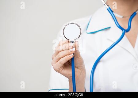 Porträt einer attraktiven jungen Ärztin Krankenschwester in weiß Mantel auf hellgrauem Hintergrund Stockfoto