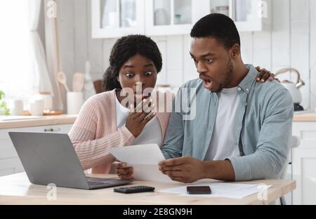 Schockiert schwarzes Paar in der Küche mit finanziellen Problemen, dabei Familienbudget Berechnungen Stockfoto