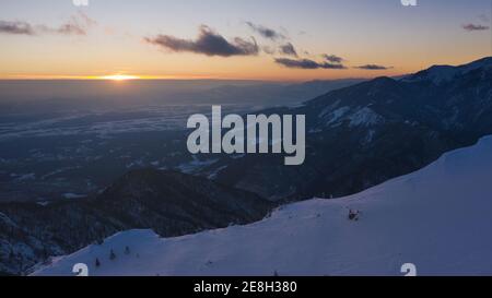 Luftaufnahme der Winterlandschaft mit schneebedecktem Fichtenwald in den Bergen mit schönem Sonnenlicht. Stockfoto