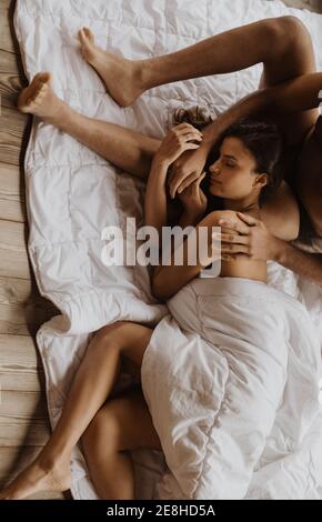 Von oben Inhalt entspannte weibliche liegend auf fit boyfriends Beine Auf weicher, kuscheliger Decke auf Holzboden Stockfoto