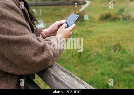 Crop von anonymen jungen molligen Weibchen im Mantel Surfen im Internet Auf dem Handy in der Stadt Stockfoto