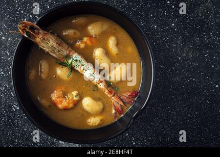 Von oben appetitlich Sahne Suppe mit weißen Bohnen und Langoustines serviert in Schale und auf Marmor-Tischplatte in Küche Stockfoto
