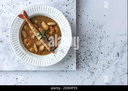 Von oben appetitlich Sahne Suppe mit weißen Bohnen und Langoustines serviert in Schale und auf Marmor-Tischplatte in Küche Stockfoto