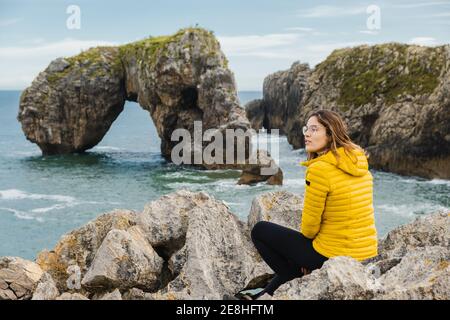 Seitenansicht einer nicht erkennbaren barfüßigen Frau im aktiven Ohr, die kniet Yoga Pose auf Matte in der Nähe von Laptop und Smartphone auf Stativ Während der Aufnahme von tutori Stockfoto