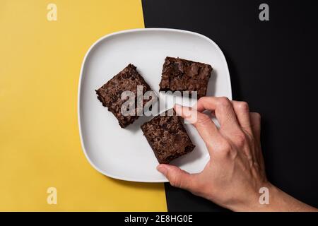 Stücke von frischem Brownie auf schwarzem und gelbem Hintergrund Stockfoto