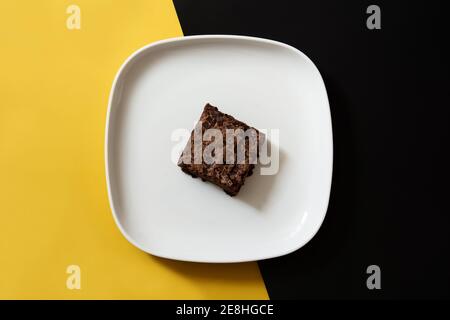 Stück frischer Brownie auf schwarzem und gelbem Hintergrund Stockfoto