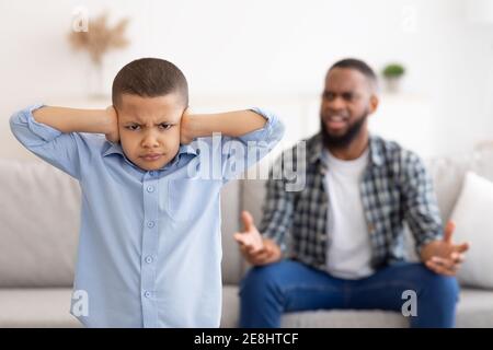 Black Boy Bedeckt Ohren Während Wütend Vater Schreiend Zu Hause Stockfoto