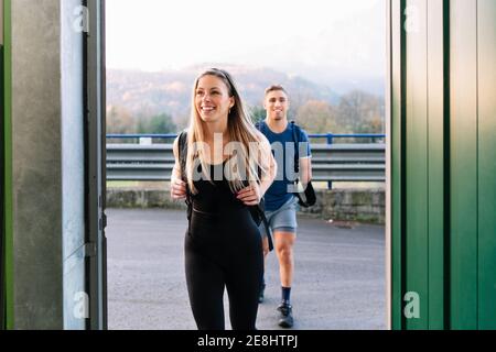 Junge, fröhliche Sportlerin und behinderte Sportlerin gehen gemeinsam ins Fitnessstudio Stockfoto