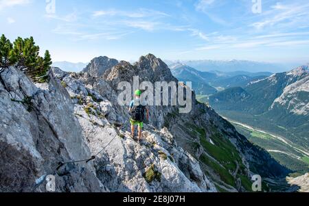 Bergsteiger steigt auf einem gesicherten Klettersteig, Mittenwalder Höhenweg, Blick ins Isartal bei Mittenwald, Karwendelgebirge, Mittenwald Stockfoto