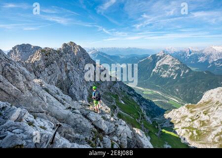 Bergsteiger steigt auf einem gesicherten Klettersteig, Mittenwalder Höhenweg, Blick ins Isartal bei Mittenwald, Karwendelgebirge, Mittenwald Stockfoto