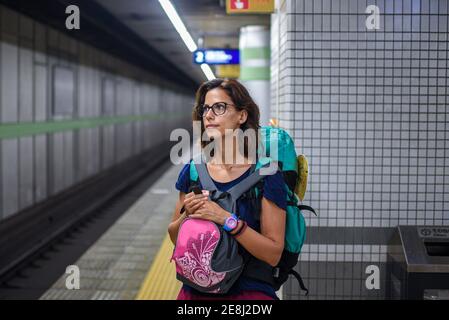 Kaukasische junge Frau mit Rucksack wartet auf einen Zug in der U-Bahn-Station, Tokio, Japan Stockfoto
