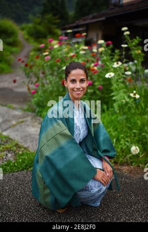 Porträt einer jungen attraktiven kaukasischen Frau in einem traditionellen japanischen Kimono, umgeben von Blumen, in einem kleinen Dorf in Ainokura, Japan Stockfoto