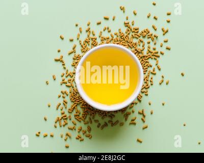 tasse Buchweizen Tee auf hellgrünem Hintergrund. Draufsicht auf gesunde Soba Tee über Leisten auf grünem Papier Hintergrund. Flach liegend. Speicherplatz kopieren Stockfoto