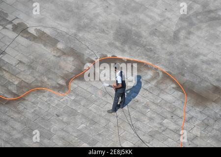 Mann Reinigung Boden mit Hochdruck Wasserstrahl Spray und Fliesen reinigen Stockfoto