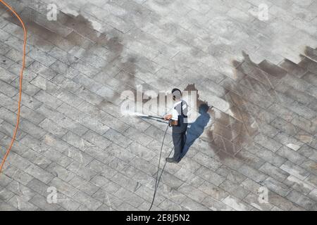 Mann Reinigung Boden mit Hochdruck Wasserstrahl Spray.Draufsicht Bild Stockfoto
