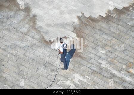Mann Reinigung Boden mit Hochdruck Wasserstrahl Spray Stockfoto