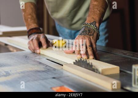 Nahaufnahme der Ernte unkenntlich Männchen ohne einen Daumen Tischler schneiden Holz mit Kreissäge in Schreinerei Stockfoto