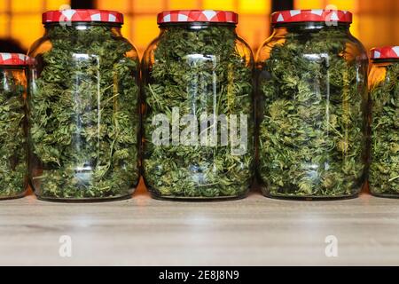 Glasgefäße gefüllt mit grünen Marihuana-Knospen und in Reihe auf Holztisch Stockfoto