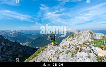 Bergsteiger steigt auf einem gesicherten Klettersteig, Mittenwalder Höhenweg, Blick ins Isartal bei Mittenwald, Karwendelgebirge, Mittenwald Stockfoto