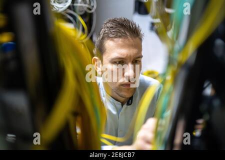 Konzentrierte männliche Spezialisten arbeiten mit Drähten in Server während der Verwaltung Netzwerk im Rechenzentrum Stockfoto