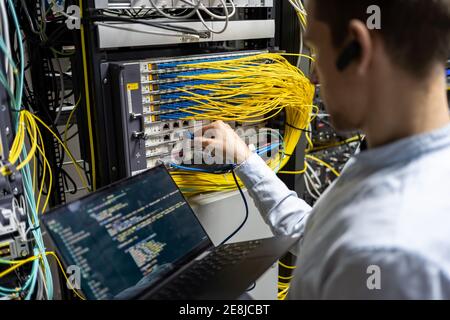 Rückansicht des Erntegut-Steckers, der das Kabel in den Router einführt Bei Verwendung eines Laptops zur Überprüfung des Netzwerksystems Stockfoto