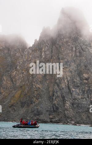 Touristen auf einem Tierkreis vor der zerklüfteten Küste von Elephant Island, South Shetland Inseln, Antarktis Stockfoto