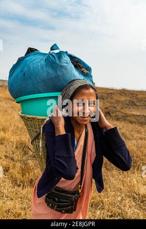 Khasi-Frau, die die Wäsche in einem traditionellen Korb zu einem Bach trägt, Meghalaya, Indien Stockfoto