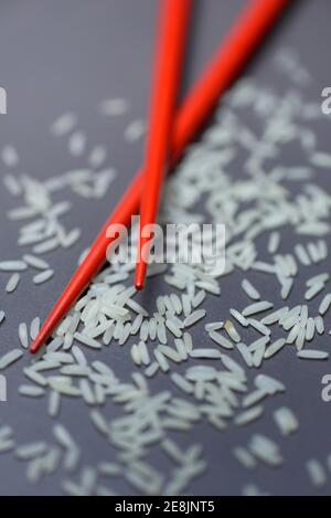 Reiskörner und Essstäbchen, Basmati-Reis, Oryza sativa, ungekocht Stockfoto