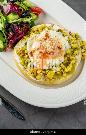 Avocado-Sandwich mit pochiertem Ei. Gehackte Avocado und Ei auf geröstetem Brot für ein gesundes Frühstück oder Snack. Stockfoto