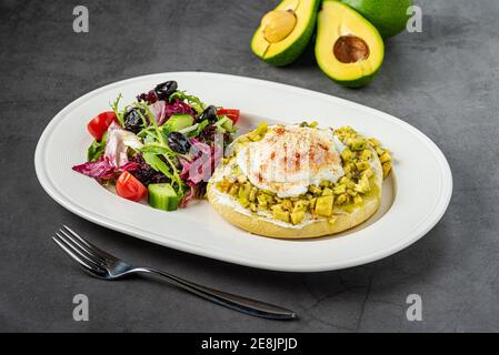 Avocado-Sandwich mit pochiertem Ei. Gehackte Avocado und Ei auf geröstetem Brot für ein gesundes Frühstück oder Snack. Stockfoto