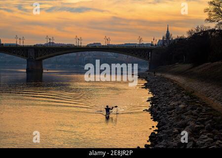 Einsame Kajaksilhouette bei Sonnenuntergang auf der Donau in Budapest. Stockfoto