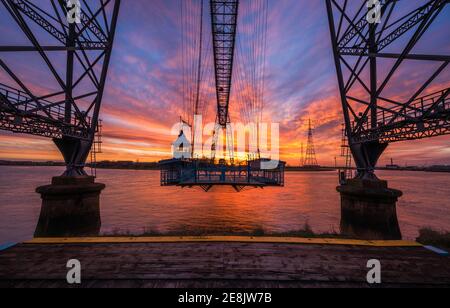 Die Sonne geht hinter der Gondel der Newport Transporter Bridge auf Stockfoto