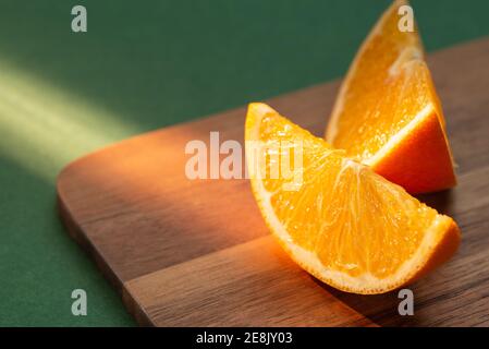 Frische Orangenscheiben auf dem Schneidebrett strahlen in den Strahlen der Abendsonne. Stockfoto