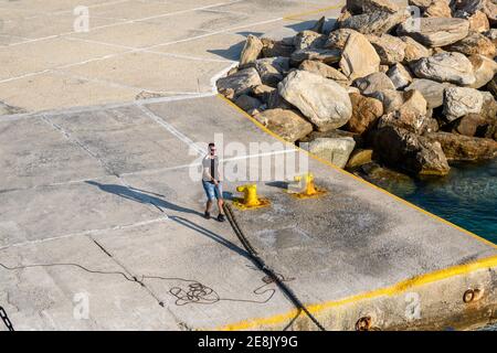 Sikinos, Griechenland - 23. September 2020: Ein Mann hält ein Seil im Hafen von Sikinos in Alopronia. Kykladen, Griechenland Stockfoto