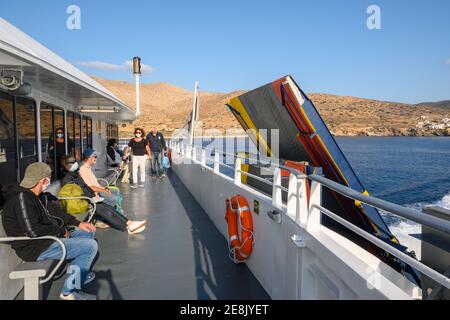 Sikinos, Griechenland - 23. September 2020: Tourist sitzt auf der Bank der Fähre. Küste der Insel Sikinos im Hintergrund. Griechenland Stockfoto